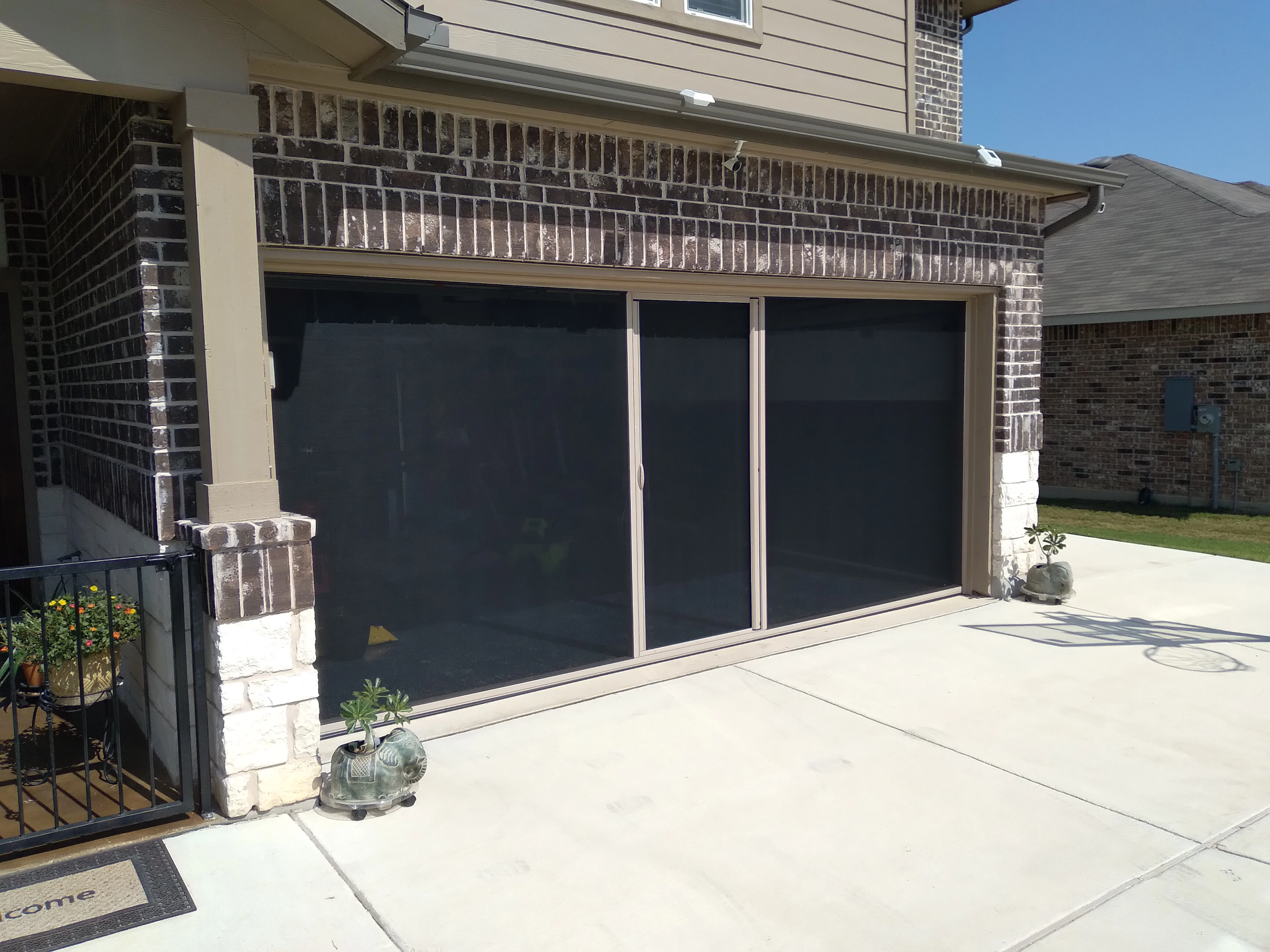 Two-car garage with dark solar screens installed on dual door panels, aluminum frame