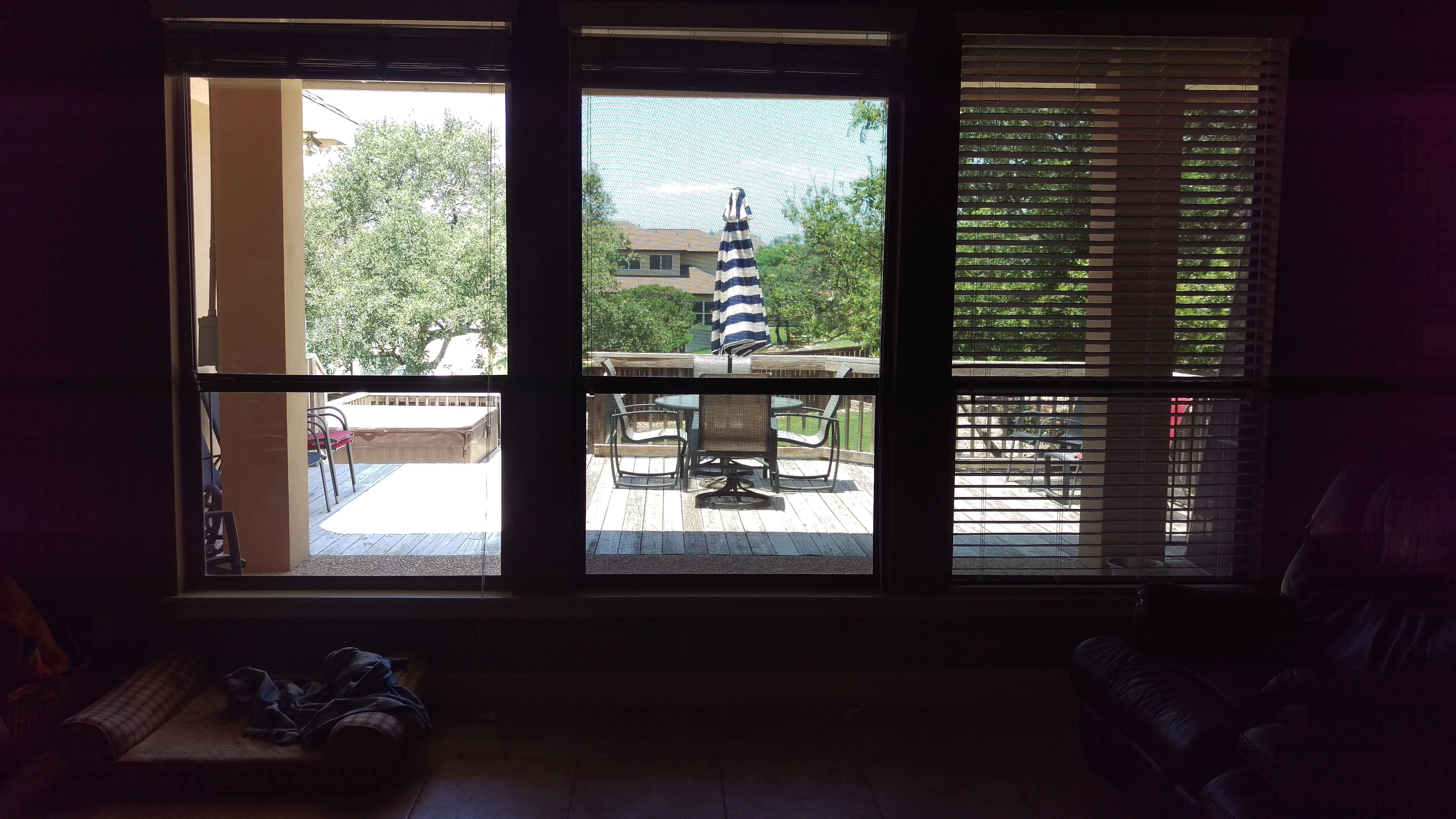 Black-framed windows with horizontal solar screens installed, view of patio and outdoor furniture