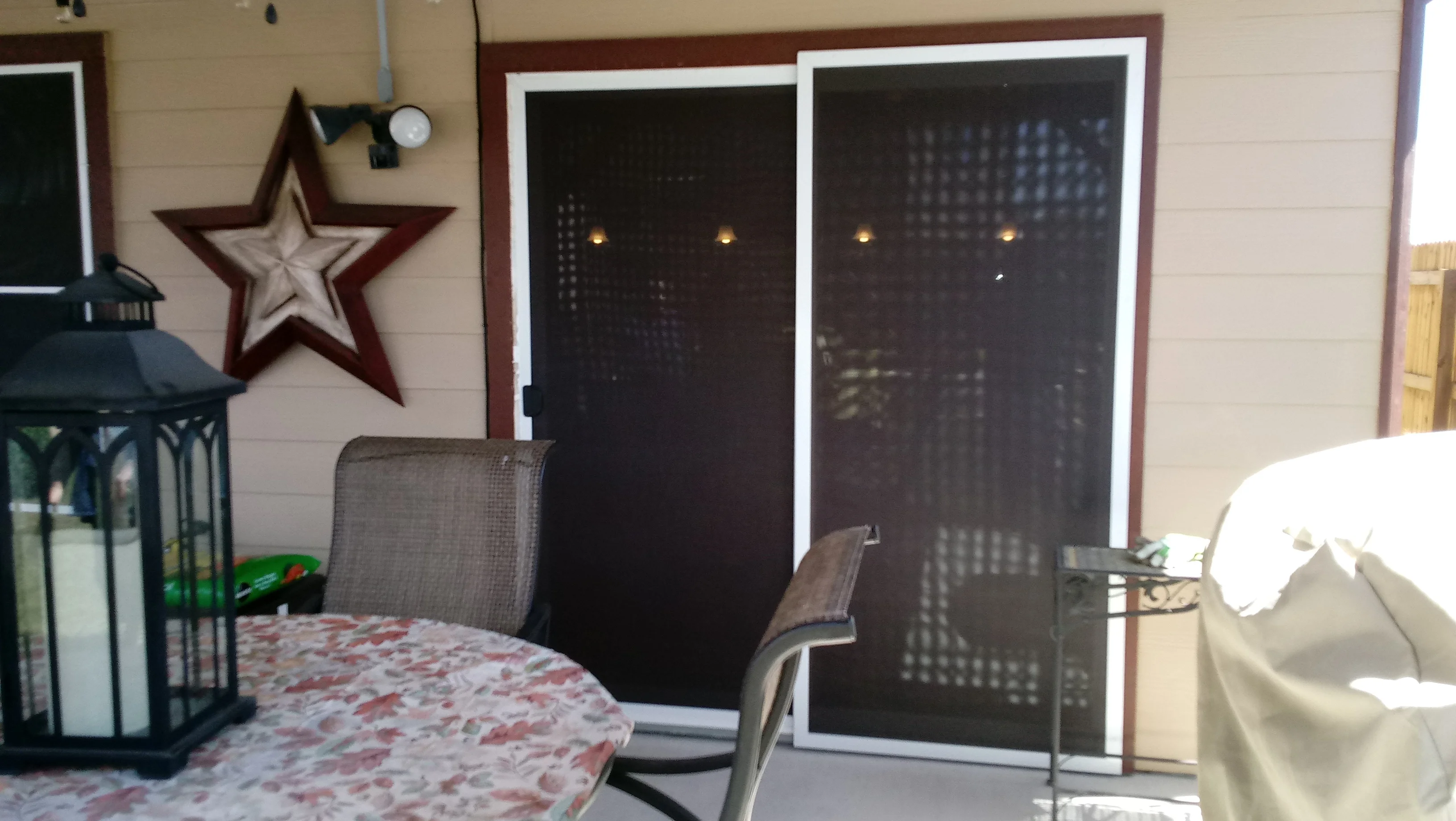 Dual sliding glass doors with dark solar mesh screens and white aluminum frames installed