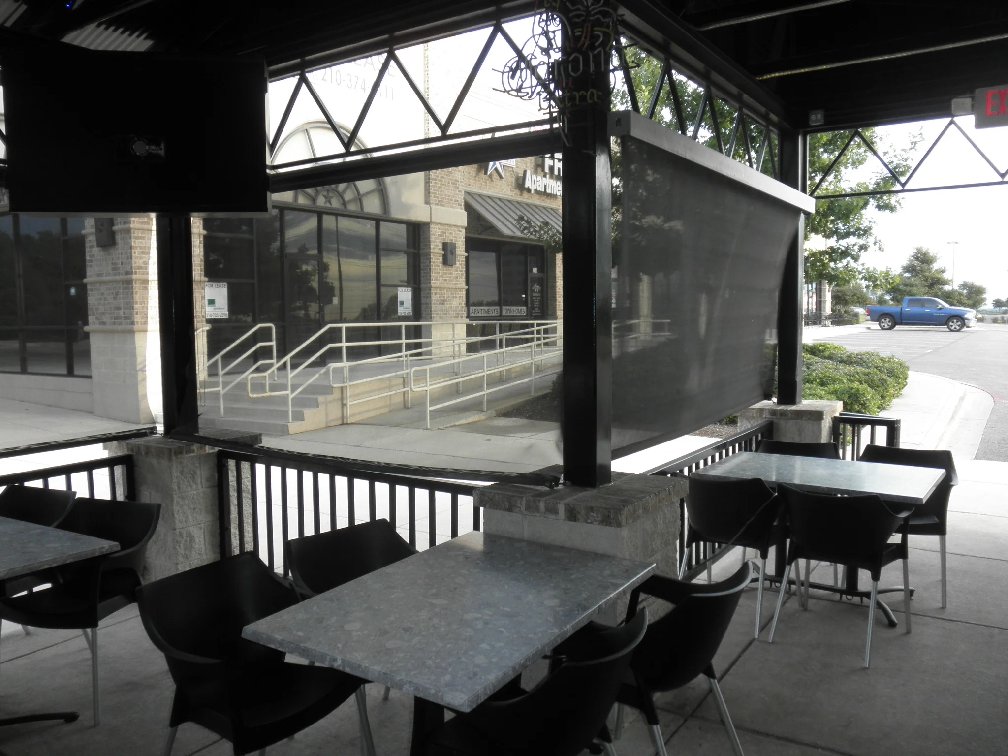 Steel patio enclosure with lattice windows, shade panels, and metal railings over concrete pad