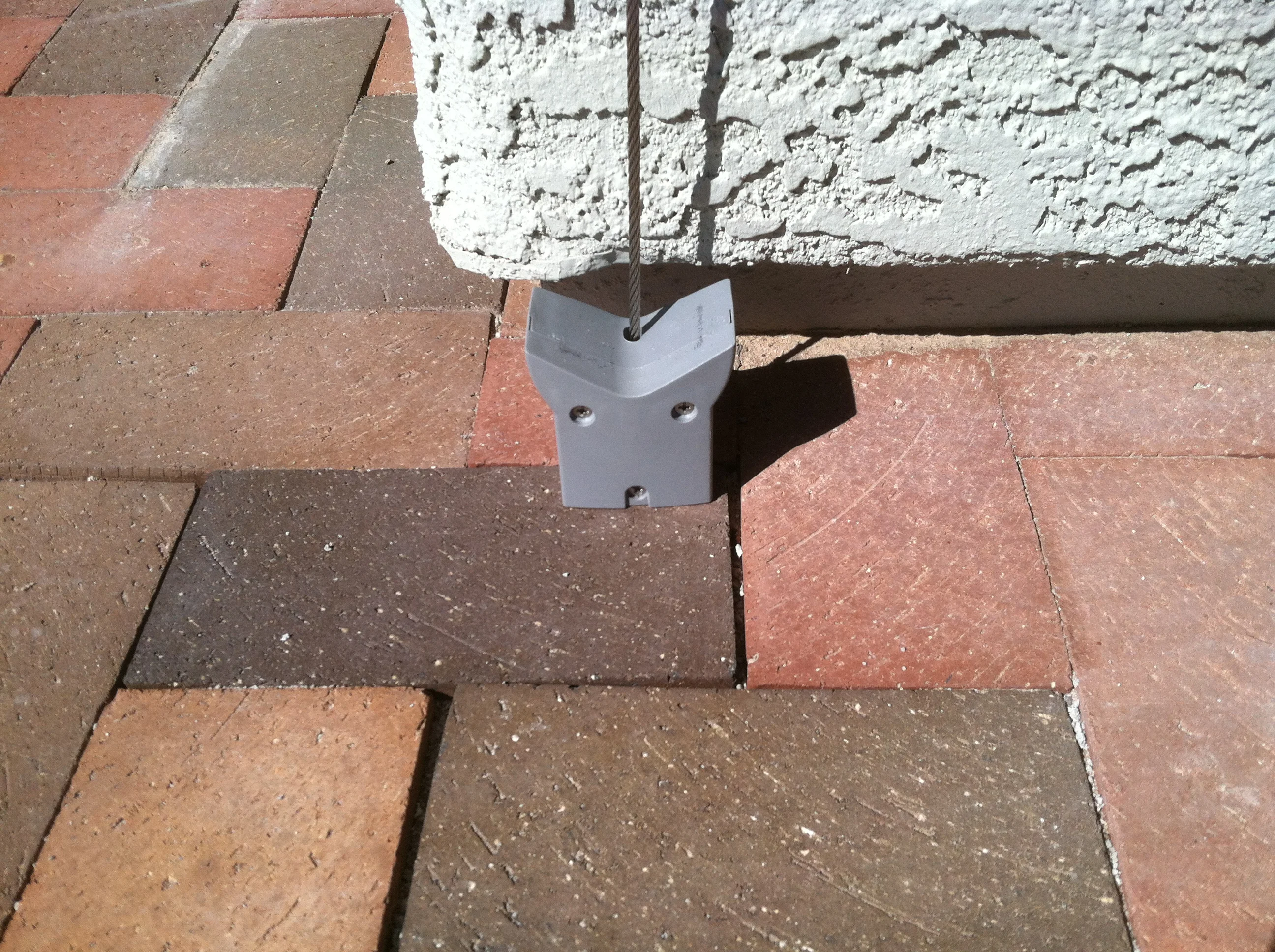 Metal bracket with cable system mounted on brick and stone exterior surfaces