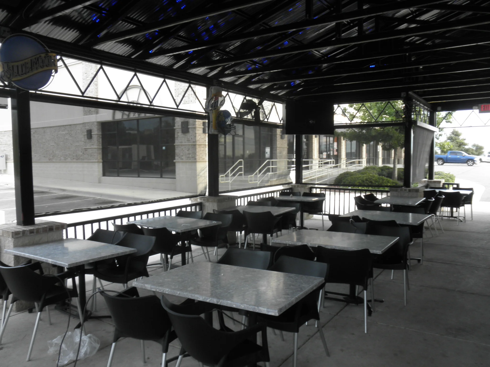 Steel patio pergola with retractable solar screens, clerestory windows, and metal railings over dining tables