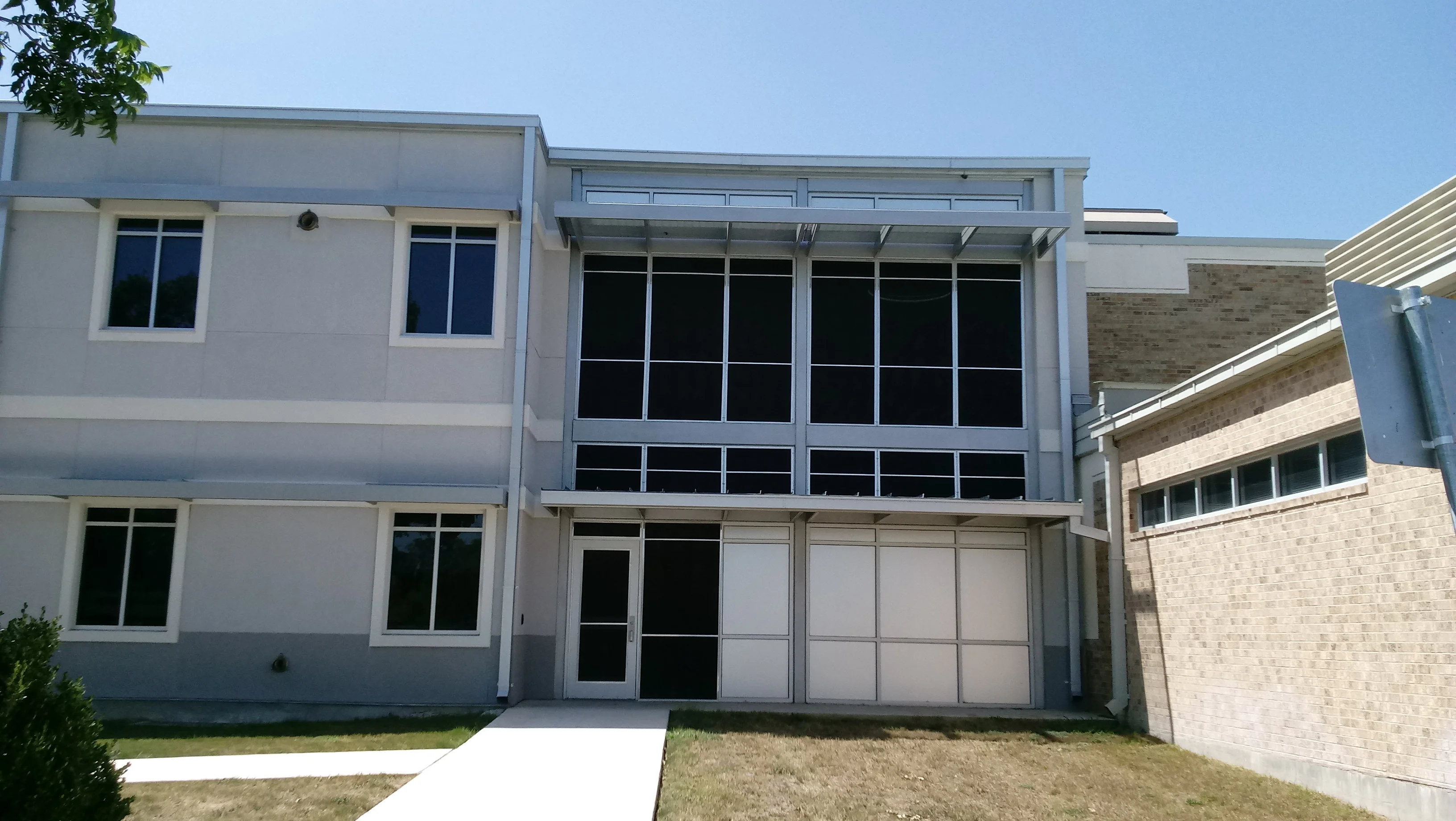 Two-story commercial building with aluminum-framed windows and white exterior cladding