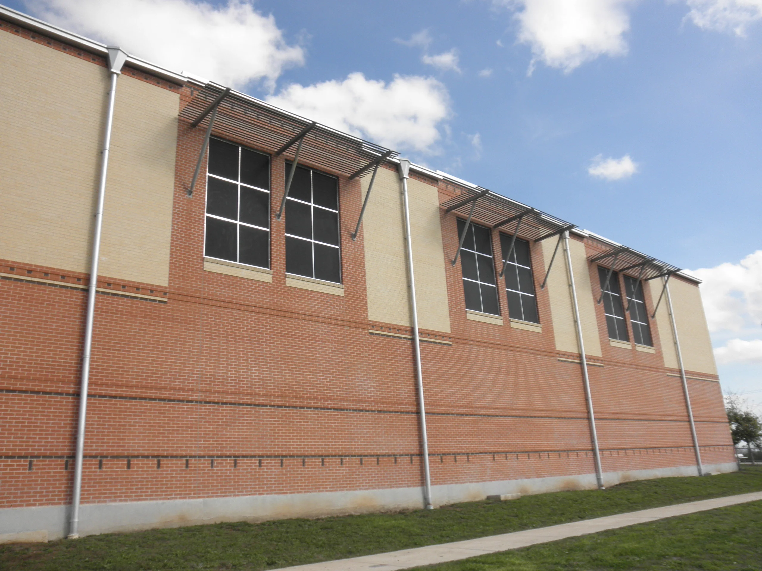 Exterior solar shade screens with horizontal slats installed on brick school building windows