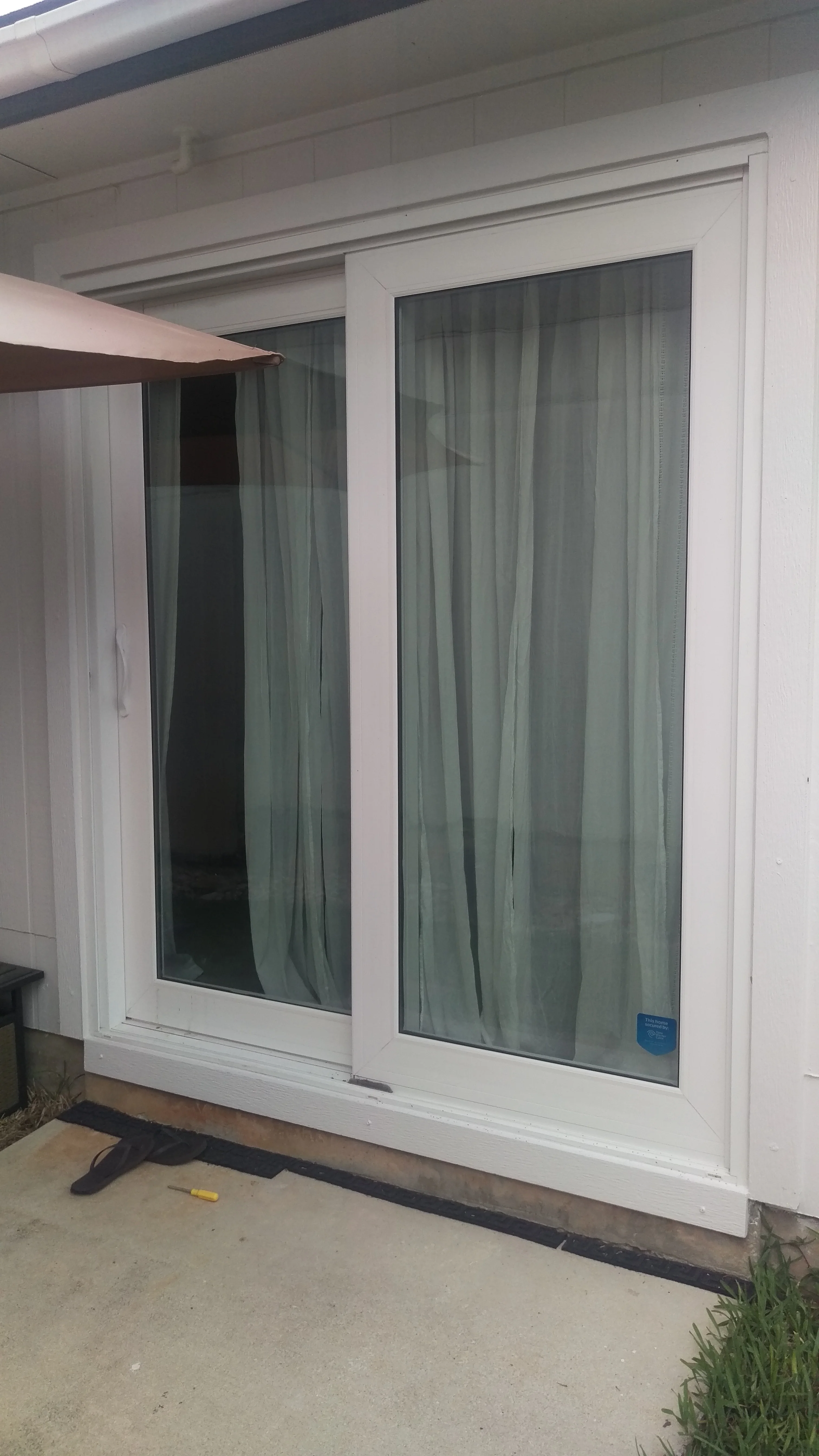 White vinyl sliding screen door with gray mesh panels and dual-track hardware installation