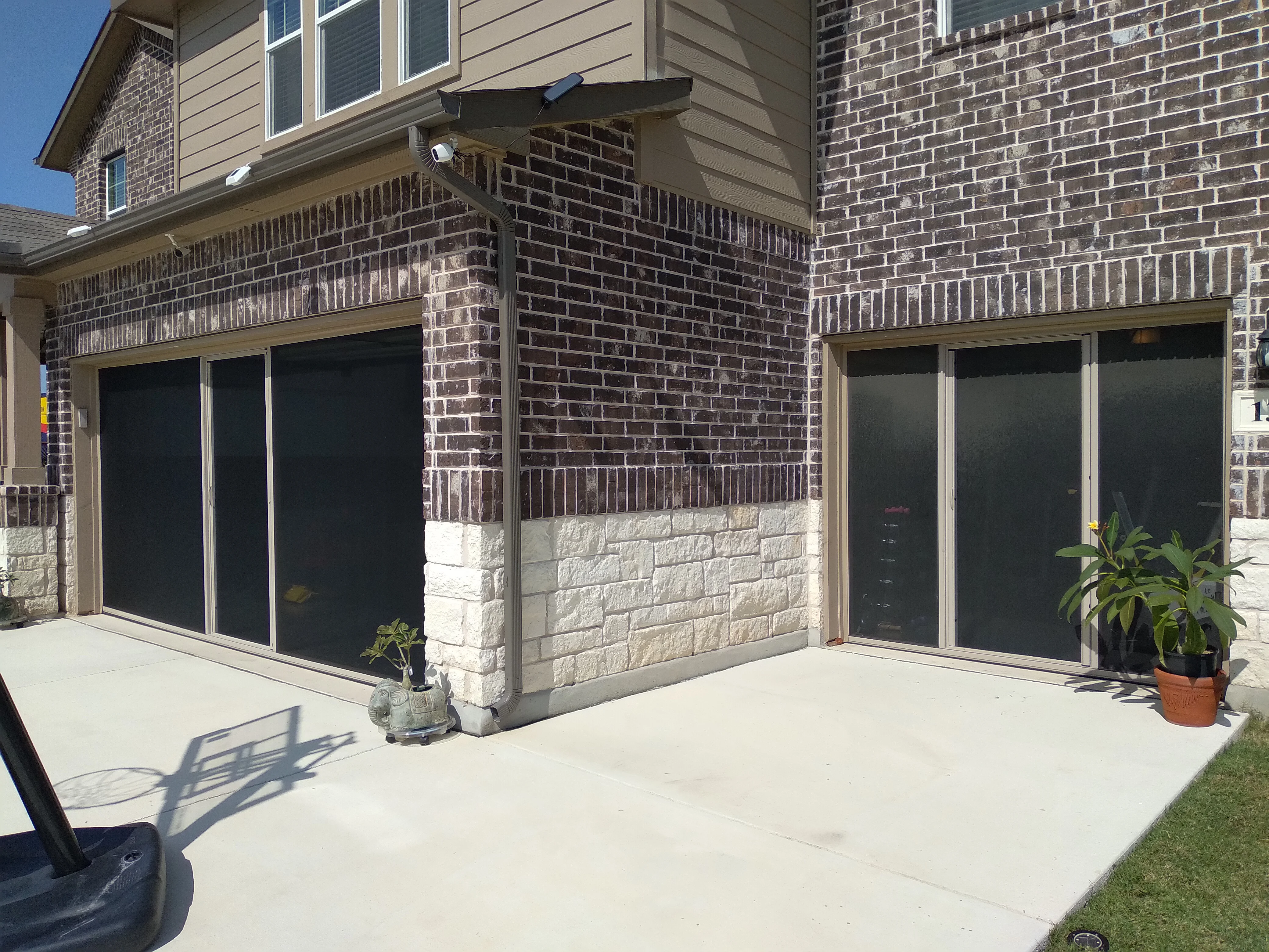 Black retractable garage screen doors with aluminum frames on brick and stone home exterior