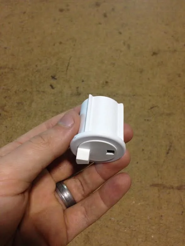 White plastic end pin component held in hand, showing connector detail for solar screen frame assembly
