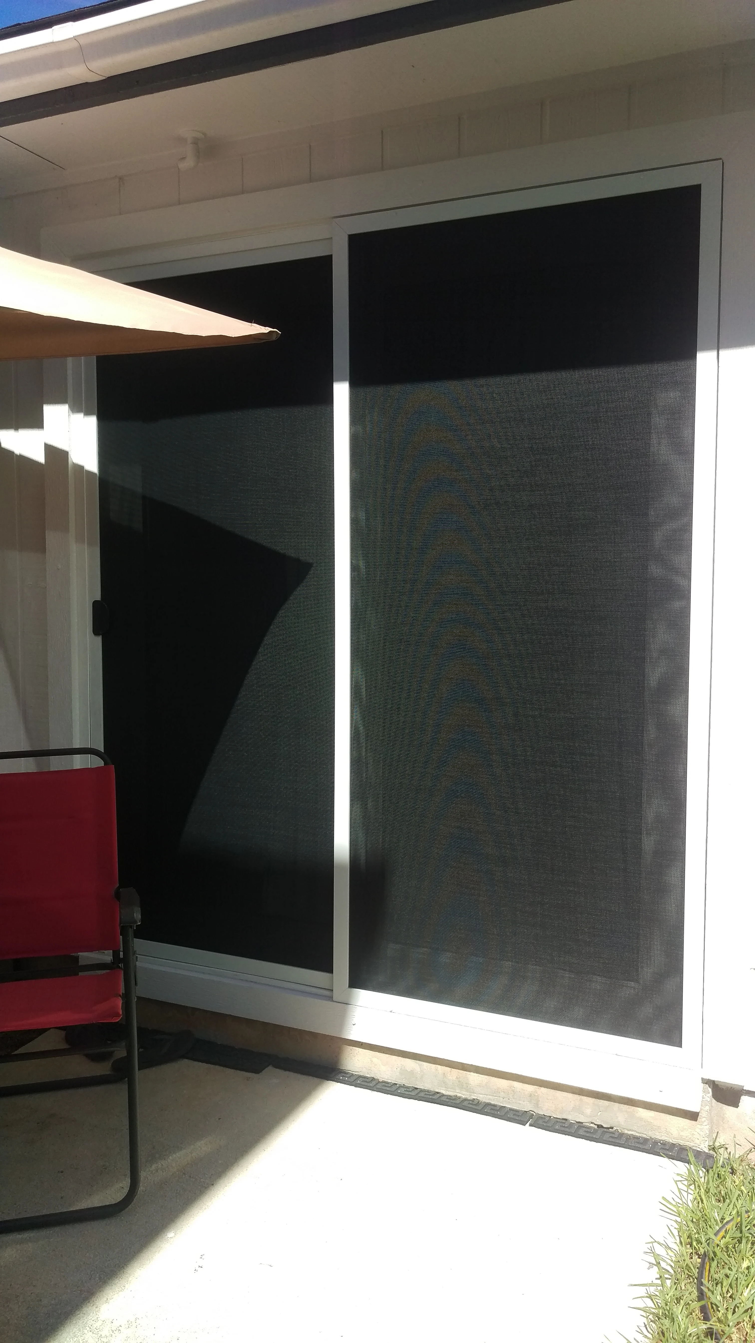 Charcoal solar screen mesh on sliding glass door with white aluminum frame