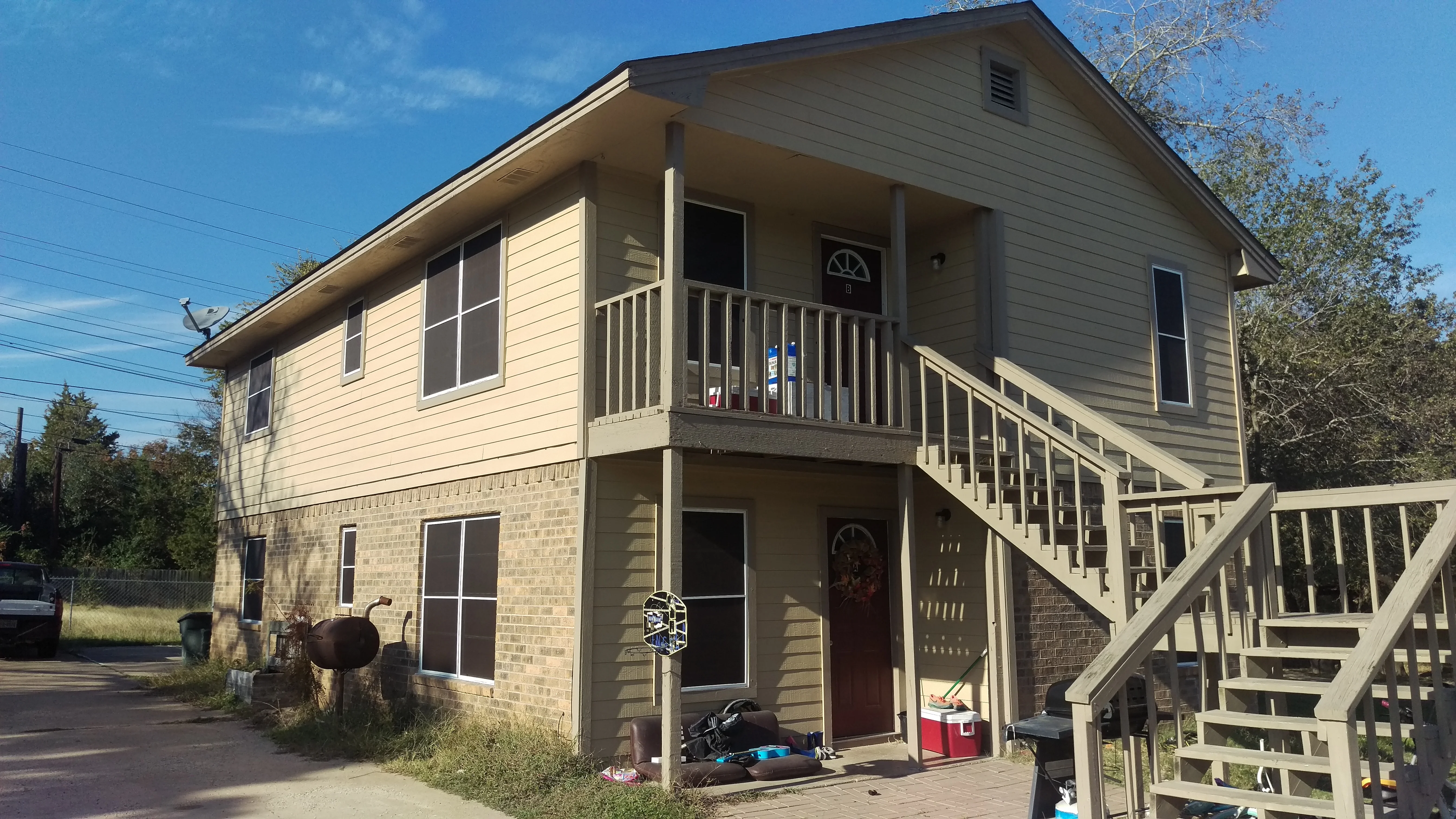 Two-story duplex with vinyl siding, new windows, composite decks, and aluminum railings on exterior stairs