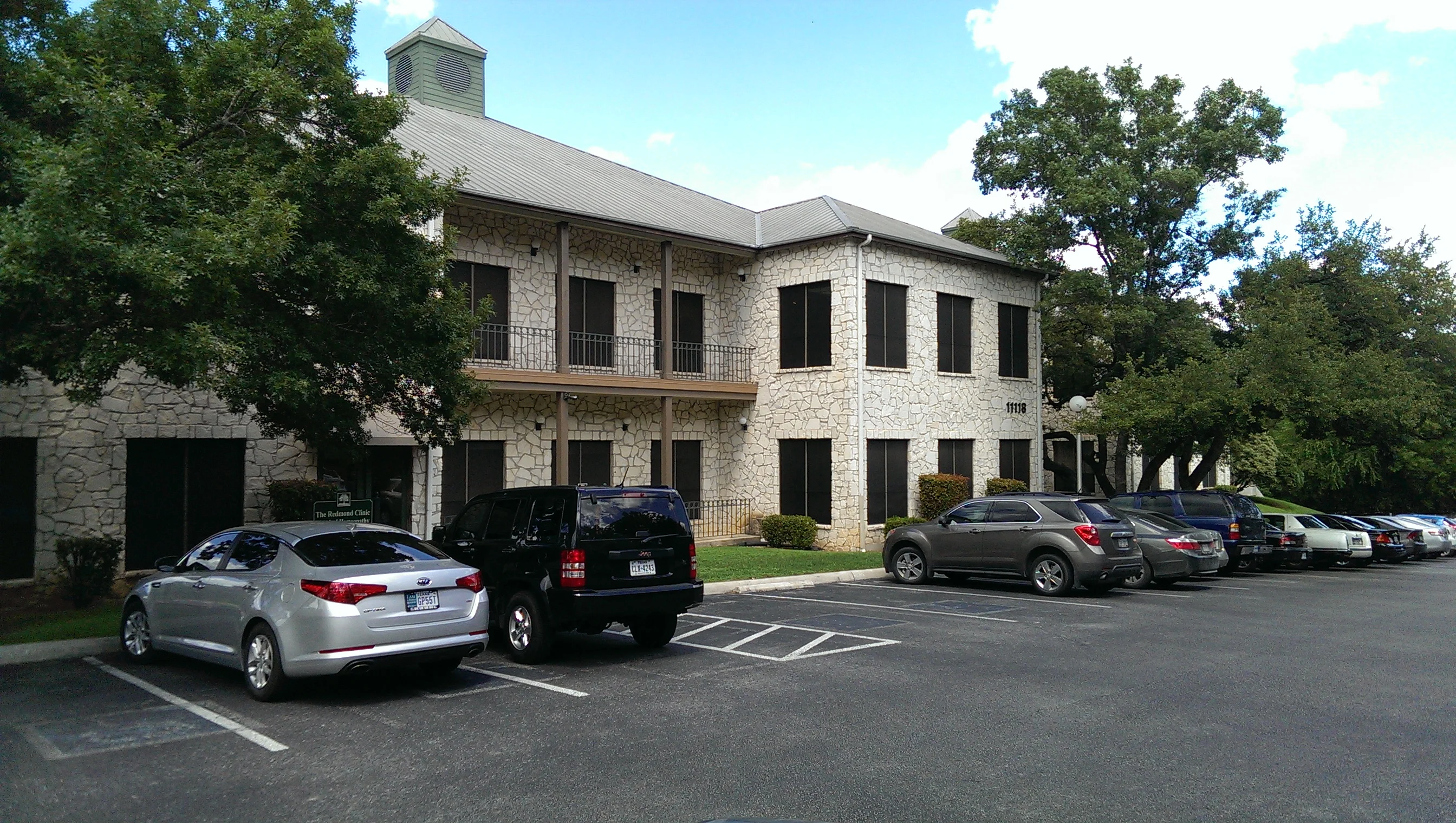 Two-story stone commercial building with black-framed windows and metal roof