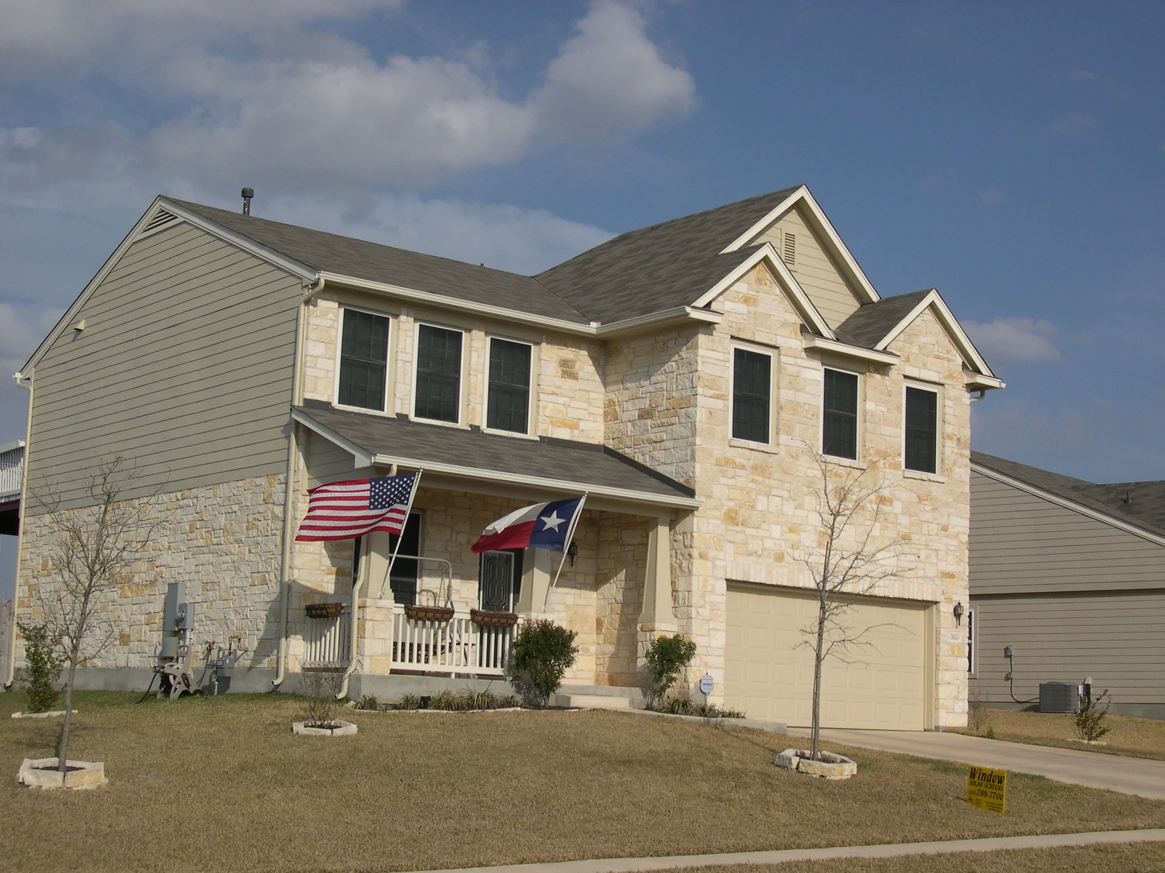 Two-story home with stone veneer and multiple black-framed windows with white trim installed on front facade