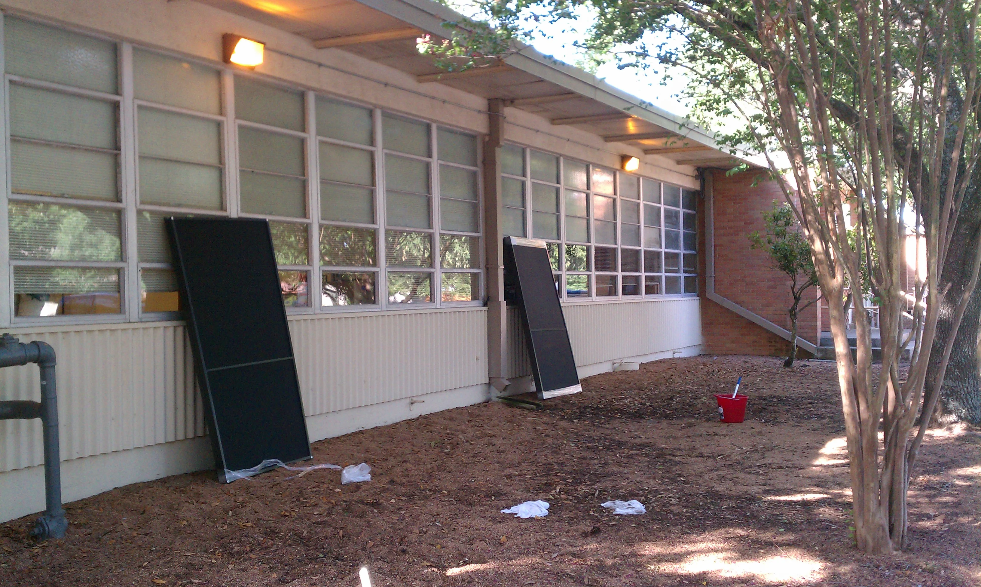 Aluminum-framed windows with solar screens installed on brick building with white wainscoting