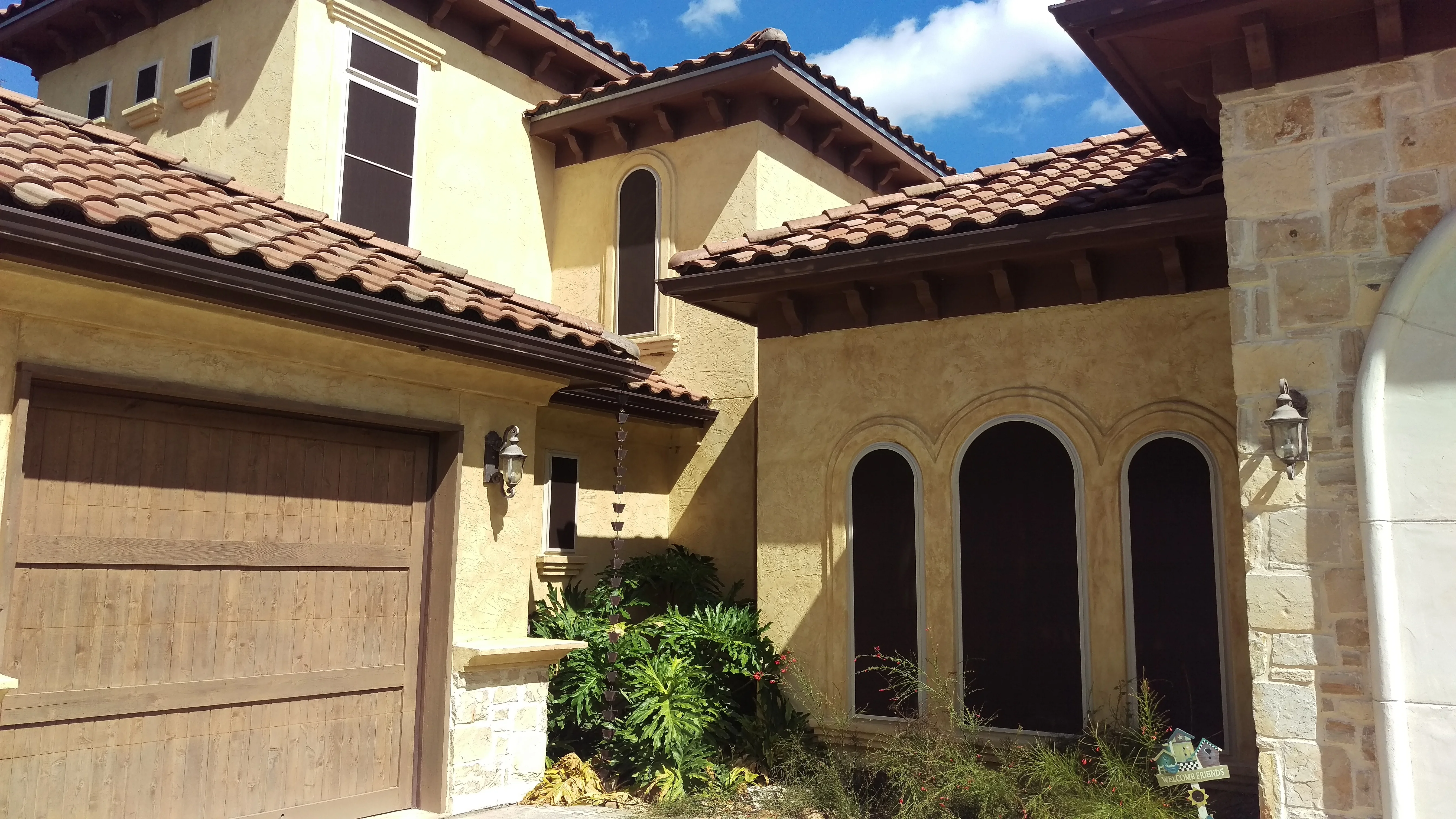 Three arched windows with dark solar screens on stucco Mediterranean home facade