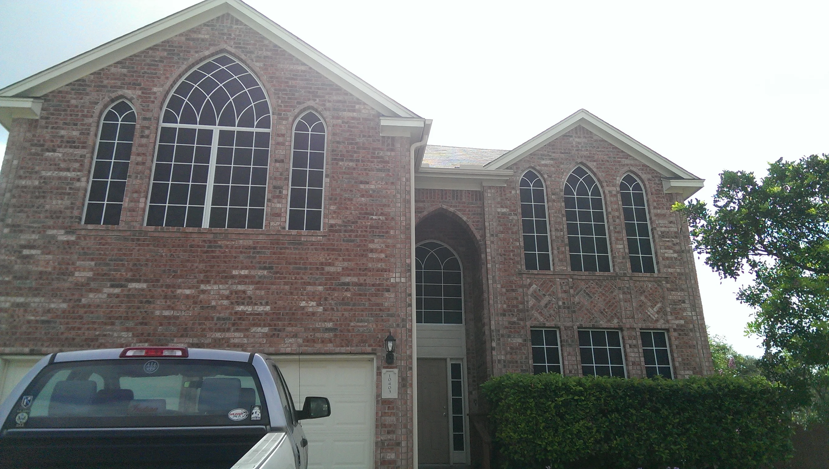 Brick home with installed arched and rectangular grid windows on two stories