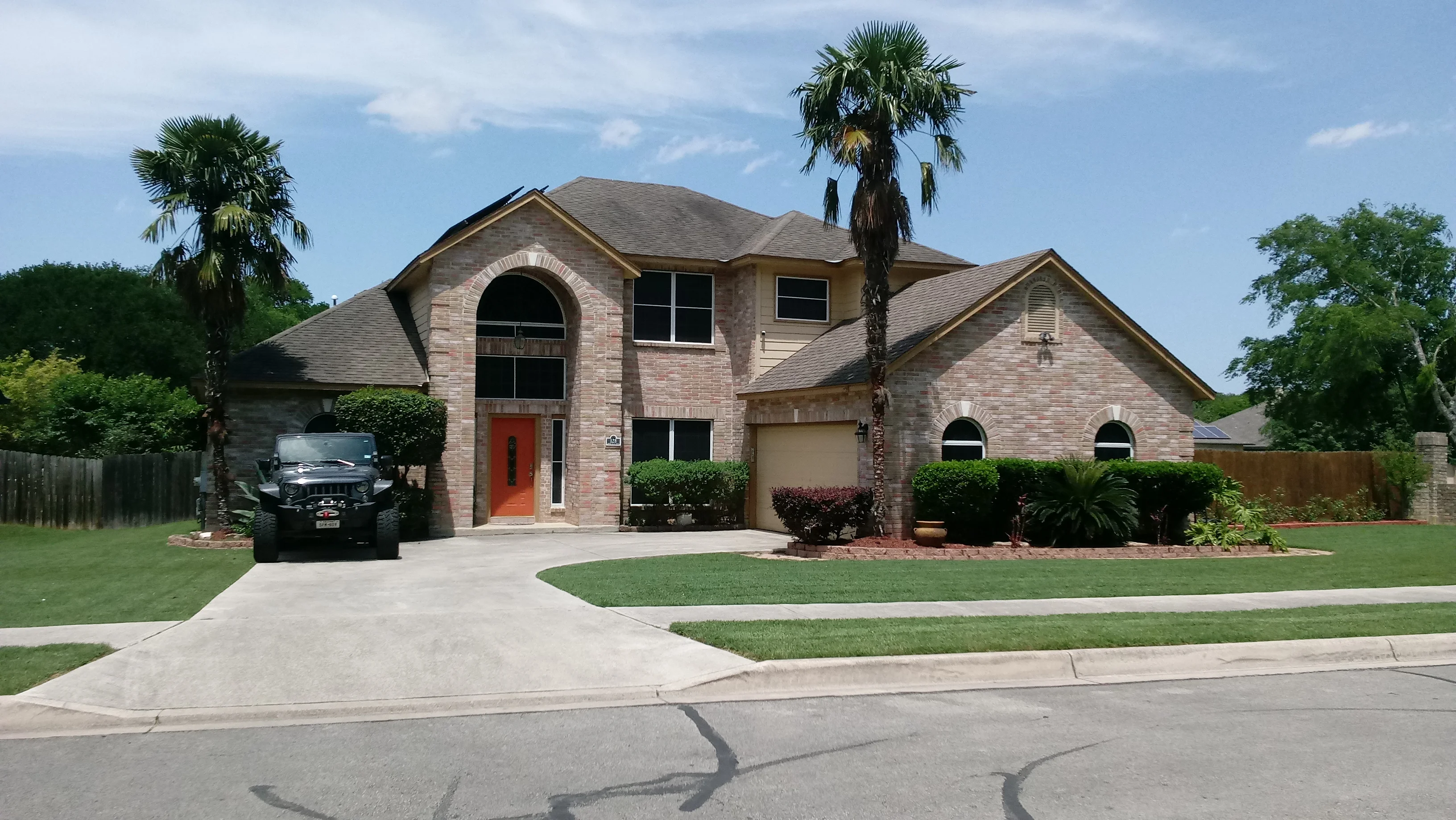 Two-story brick home with newly installed arched and rectangular windows on front facade