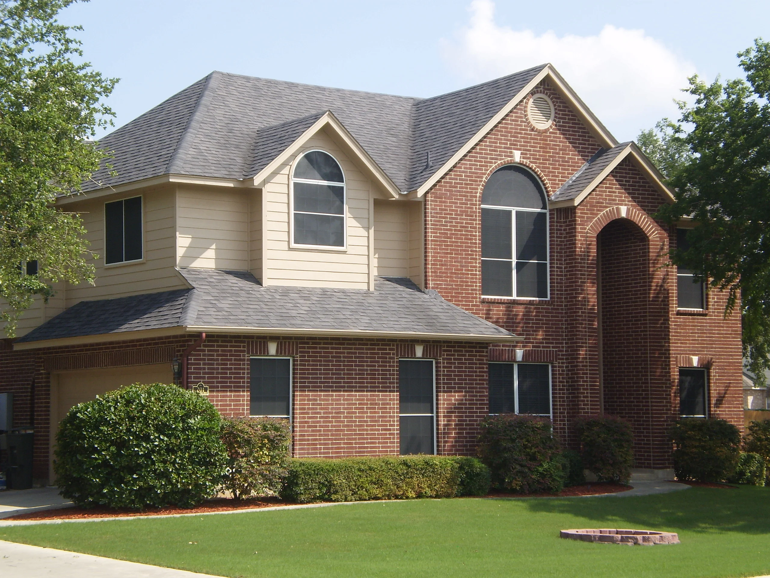Two-story brick home with newly installed arched and rectangular windows on upper and lower levels