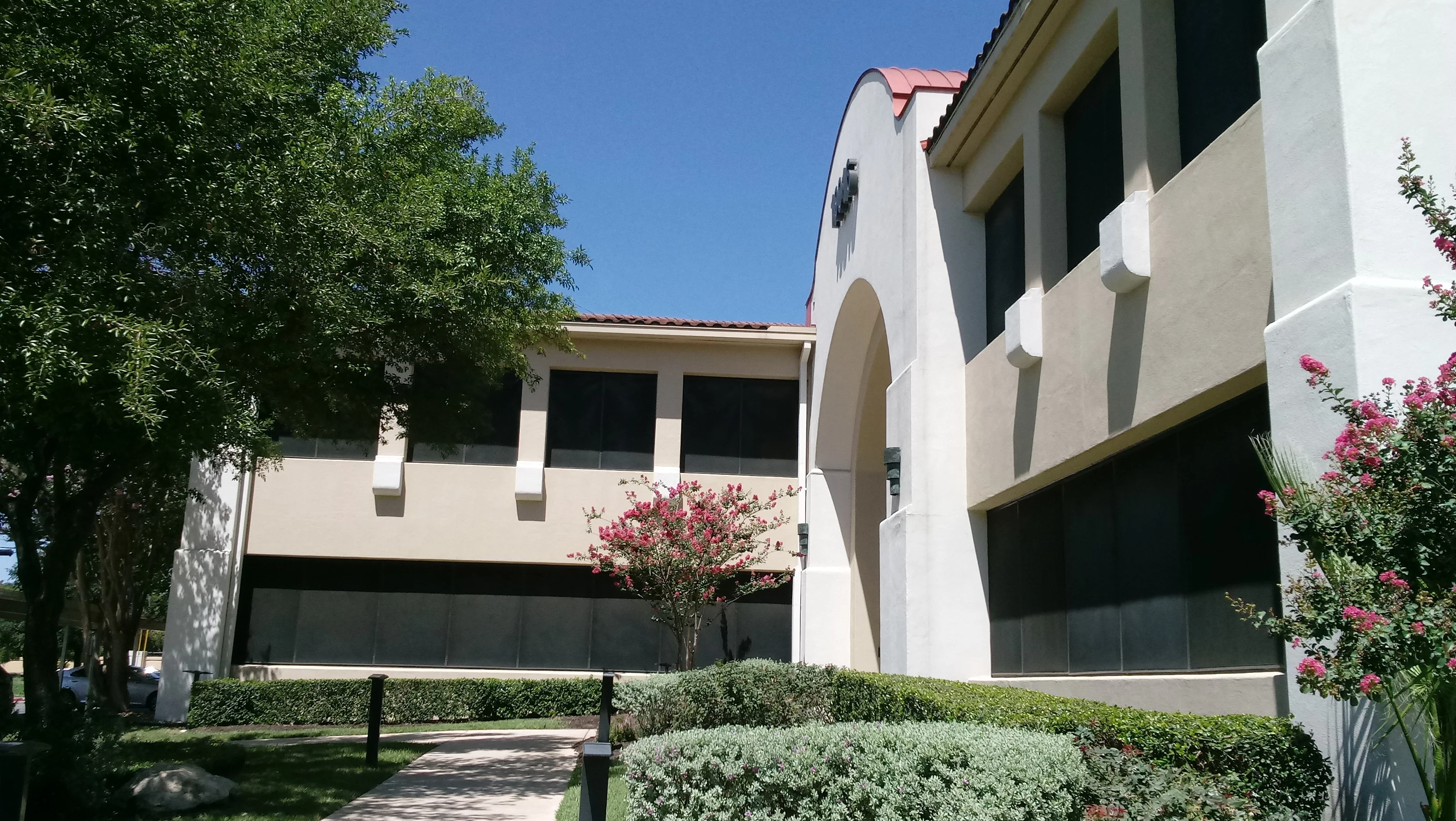 Dark solar screens installed on commercial building windows with white stucco facade
