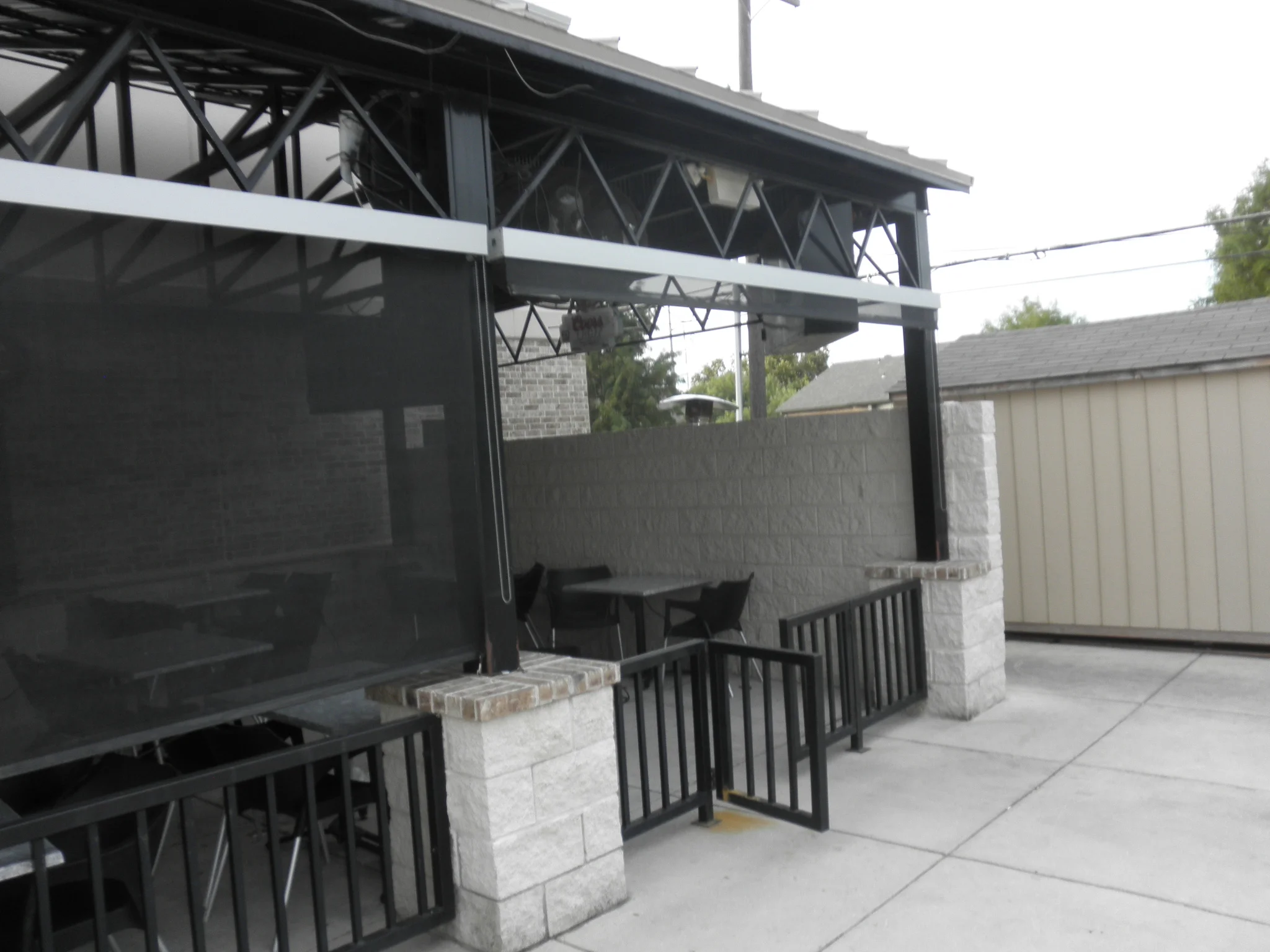 Steel patio frame with motorized solar screens, metal railings, and pergola roof structure